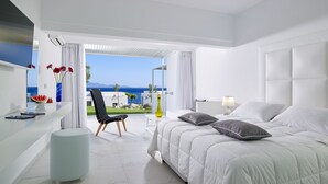 Een moderne hotelkamer met een groot bed, een stoel, een tafeltje en uitzicht op zee.