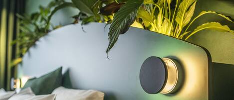 Una habitación moderna con una pared de acento verde, una cama con ropa de cama blanca y una planta en maceta en la pared.