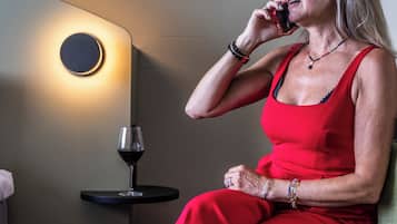A woman in a red dress sitting on a bench, holding a wine glass.