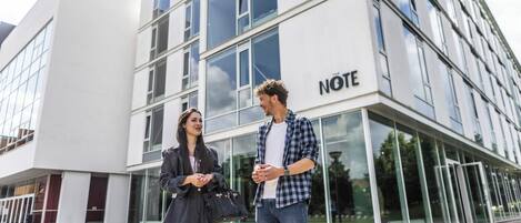 Un edificio moderno con fachada de vidrio y la palabra "NOTE" en el lateral.