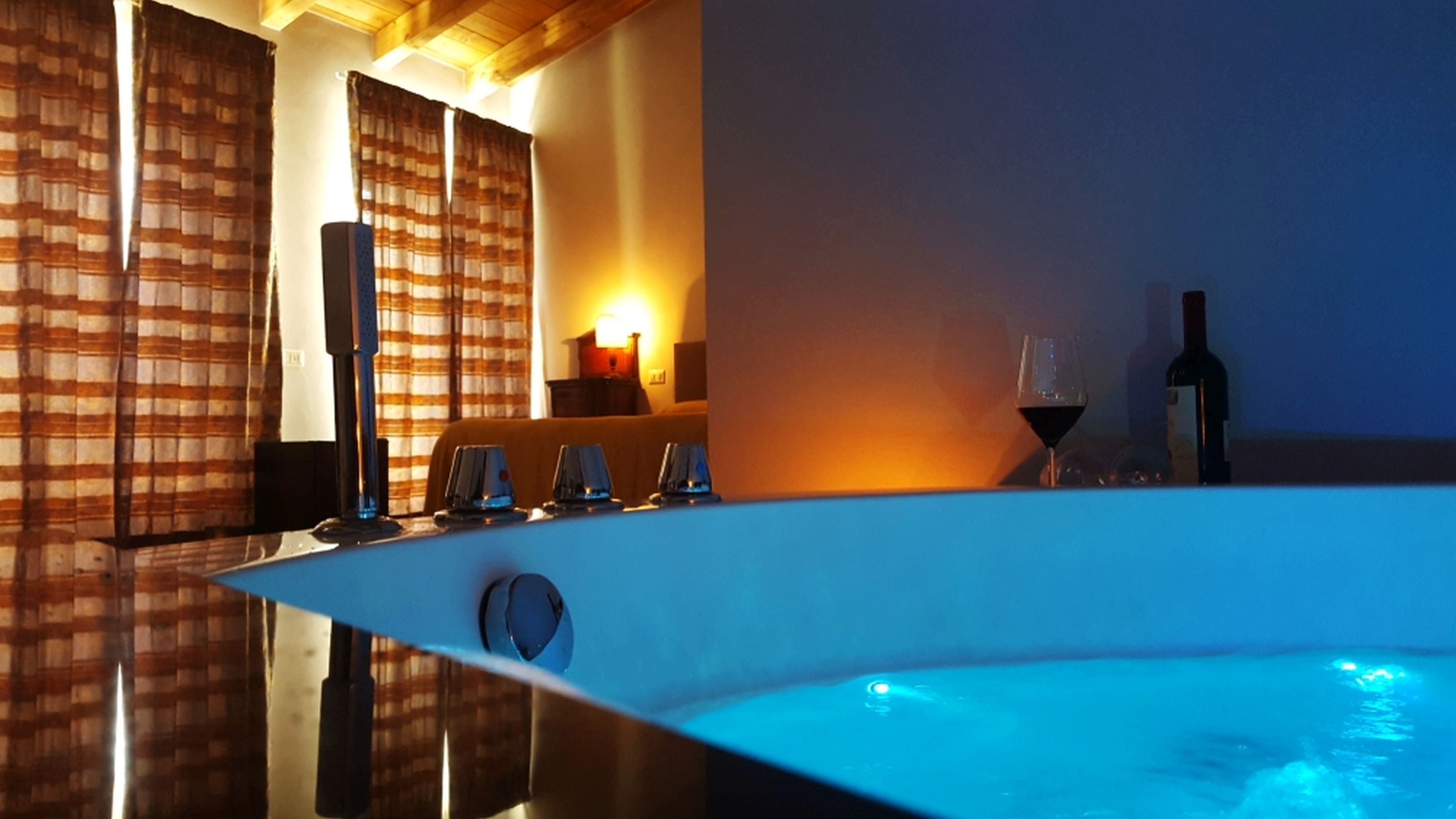 A spa area with a hot tub, a wine glass, and a bottle of wine.