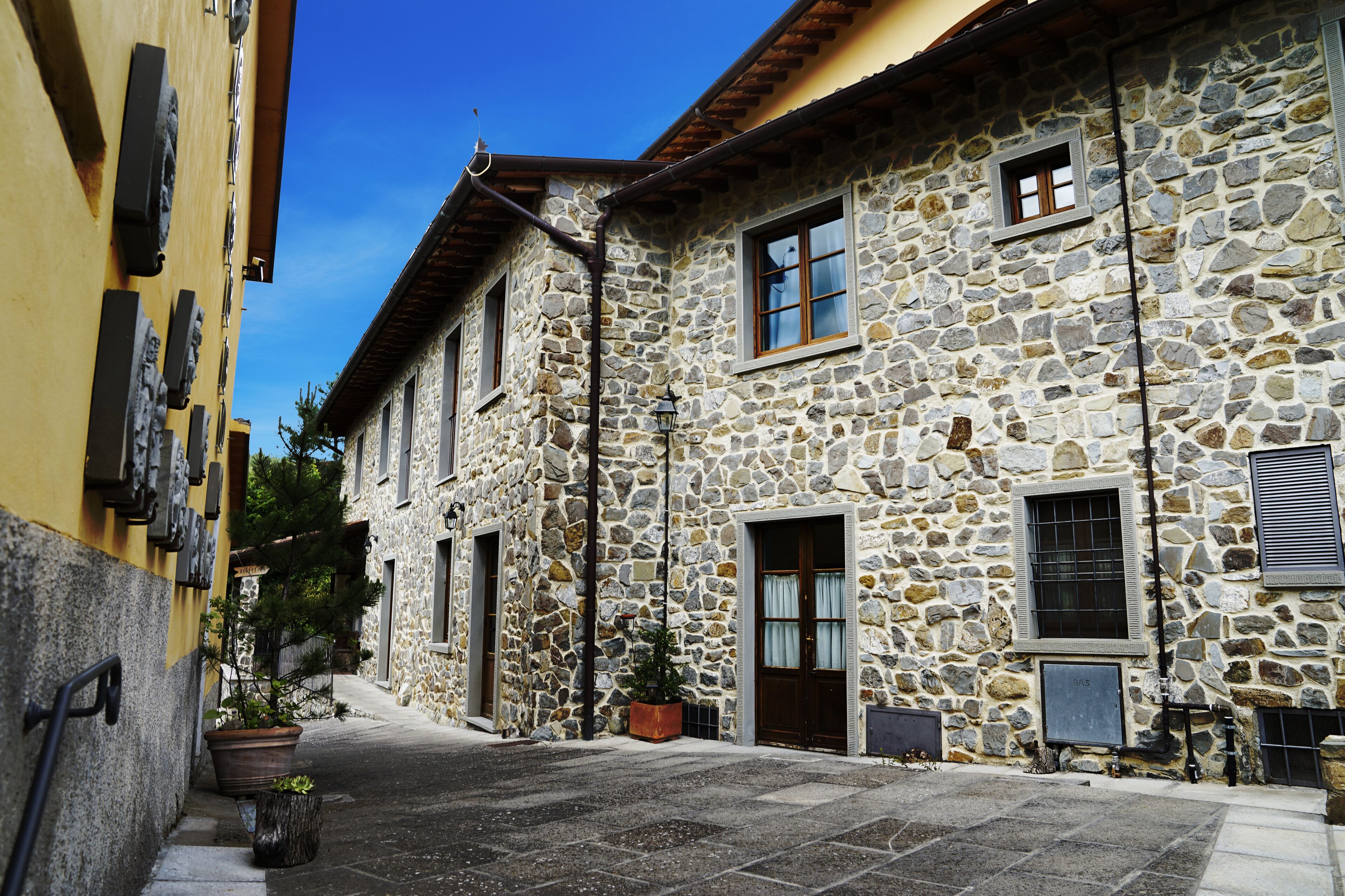 Un bâtiment en pierre avec une façade jaune, une porte en bois et une petite fenêtre.