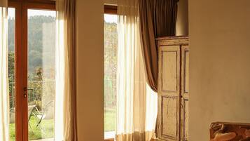 A spacious room with a large window, a wooden cabinet, and a chandelier.