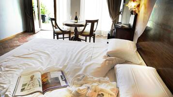 Une chambre d’hôtel avec un grand lit, une table de chevet avec une bouteille et des verres, une chaise et une vue sur l’extérieur.
