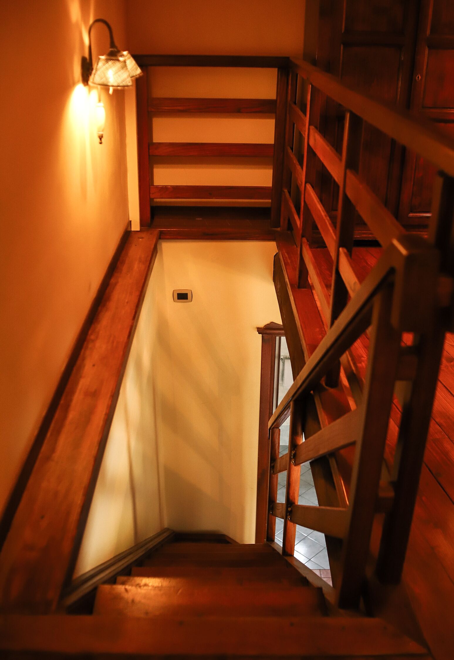 Eine Holztreppe mit Handlauf und einer Wandleuchte.