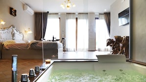A hotel room with a large bed, a bathtub, and a dining area with a table and chairs. - Borgo I Tre Baroni (Poppi)