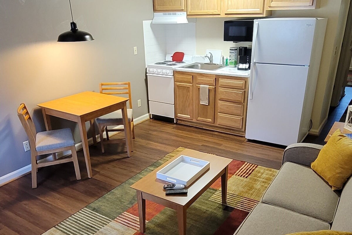 Un espace de vie compact comprenant un coin repas, un canapé et une kitchenette.