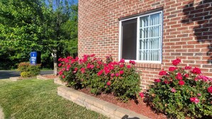 A brick building with a window and a sign for Abundant Corporate Suites. - Affordable Suites of America Harrisonburg (Harrisonburg)