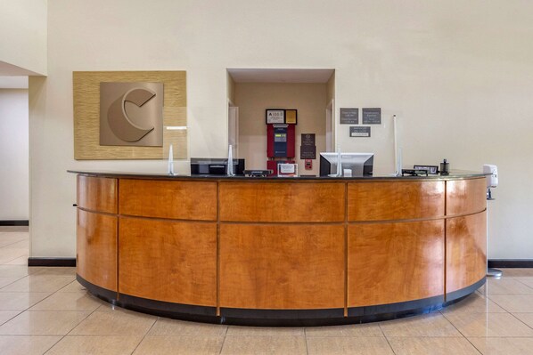 A reception desk with a wooden finish, a framed sign above it, and a fire extinguisher to the right.
