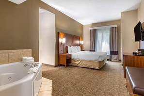 A hotel room with a large bed, a separate bathroom with a bathtub, a desk, and a television.