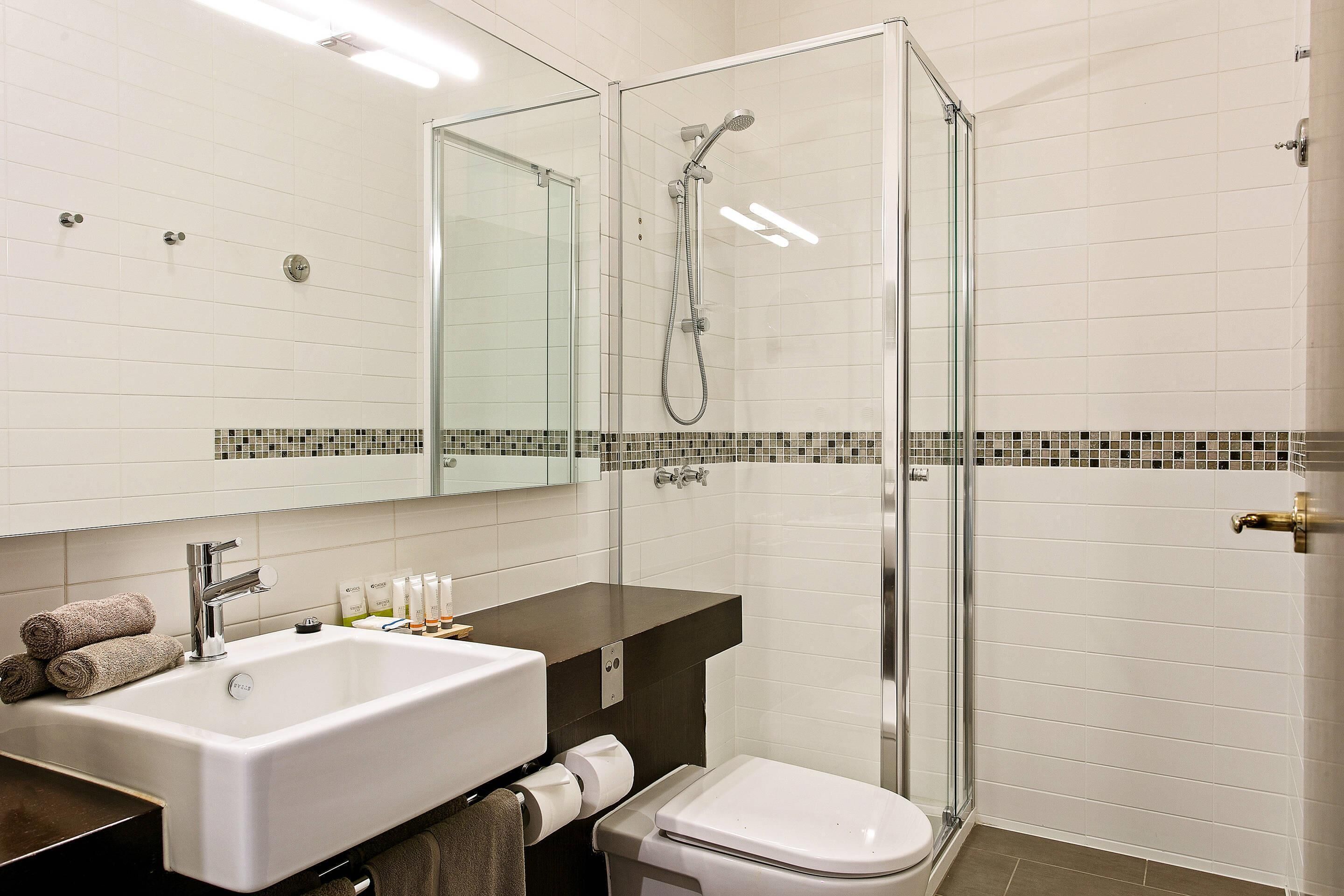 A modern bathroom with a glass-enclosed shower, a white sink, and a toilet.