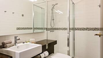 A modern bathroom with a glass-enclosed shower, a white sink, and a toilet.