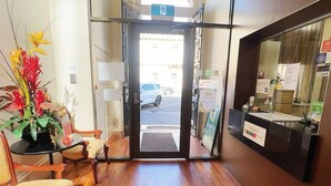 A reception area with a wooden floor, a reception desk, and a large window offering a view of the street.