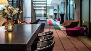 A modern interior with a long wooden table, black leather chairs, a decorative vase, and a colorful carpet. - Quality Hotel 33 (Oslo)