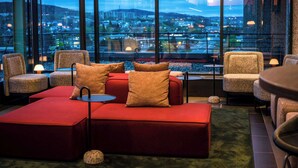 A modern lounge area with red seating, a small table, and large windows offering a city view. - Quality Hotel 33 (Oslo)