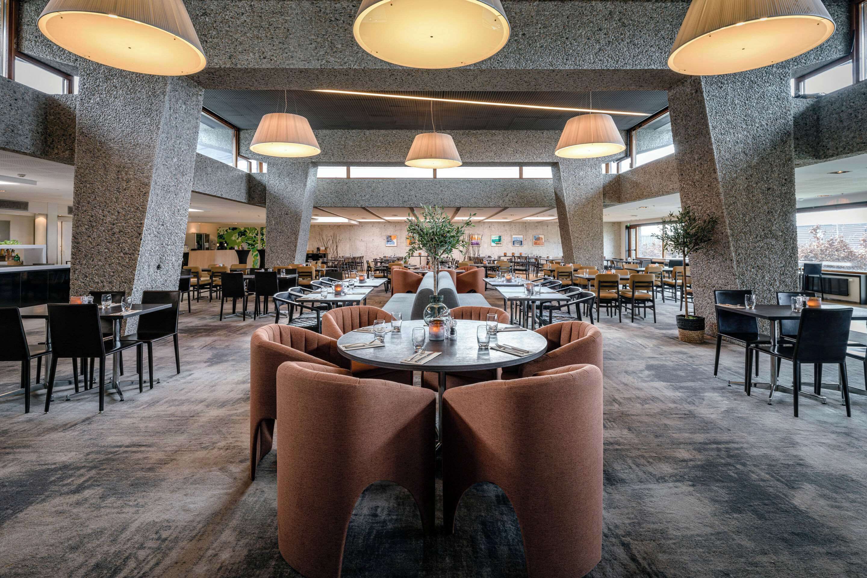 A spacious dining area with high ceilings, large windows, and modern furnishings.
