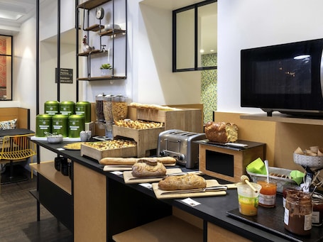 A breakfast bar with various breads, pastries, and condiments.
