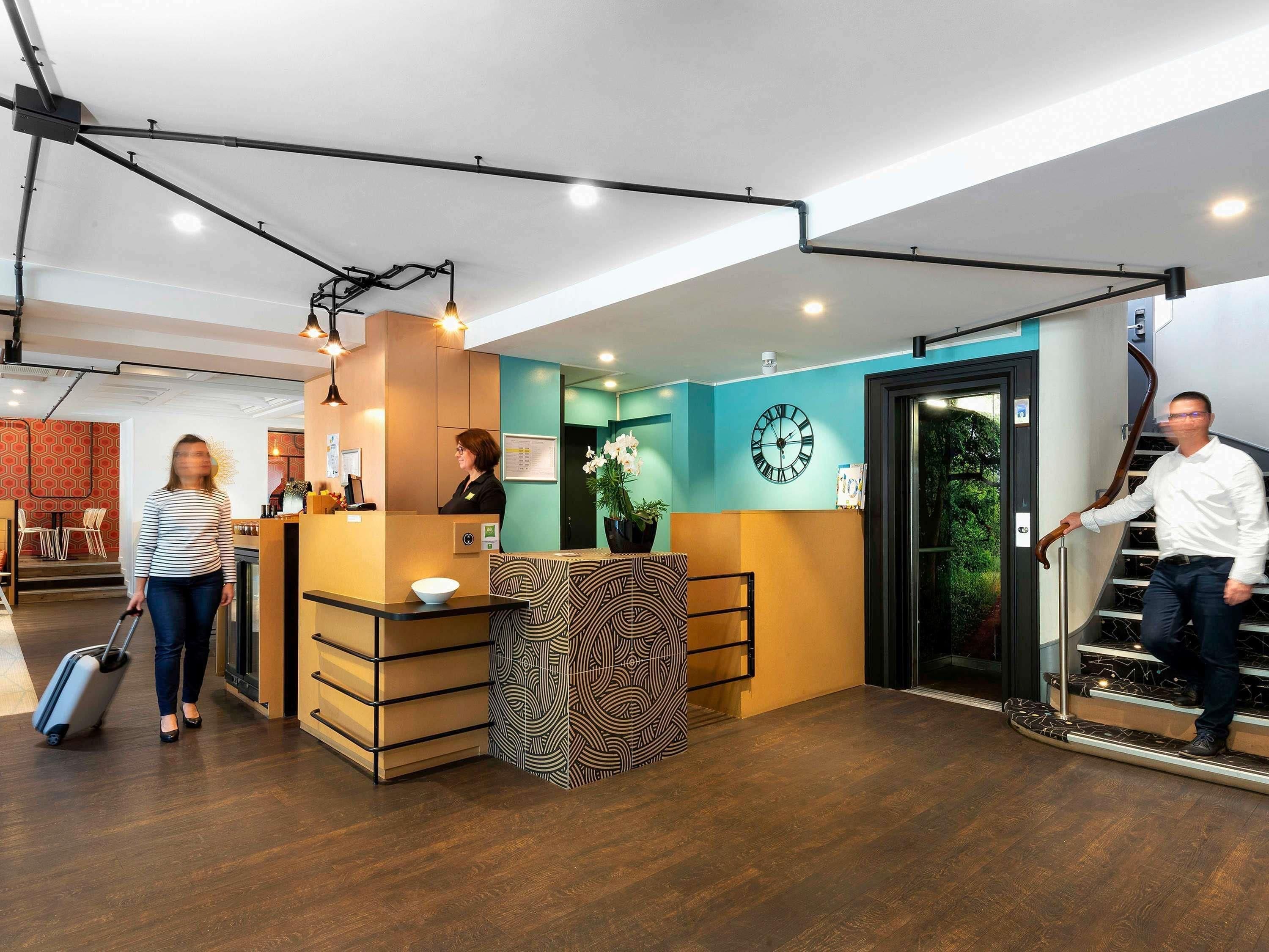 Zona de recepción con mostrador, un reloj y una escalera.