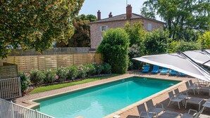 Une piscine rectangulaire avec une terrasse carrelée, entourée d’une clôture en métal blanc.