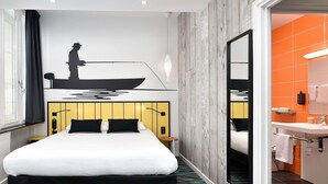 A hotel room with a bed, a large mirror, an orange bathroom, and a wall mural. - ibis Styles Macon Centre (Macon)