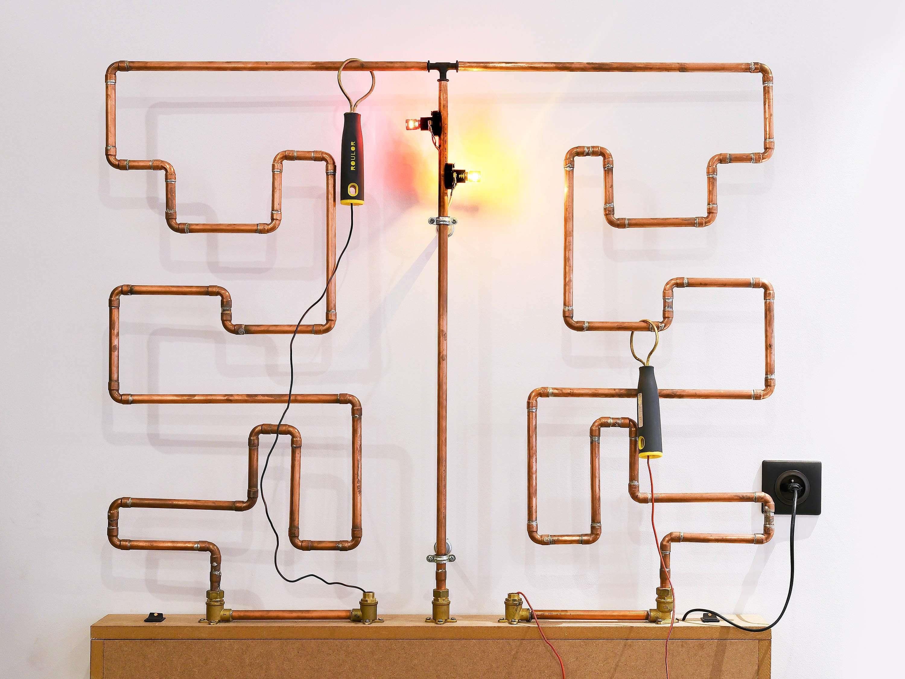 Una estructura de tuberías de cobre con válvulas y un cuadro de interruptores.