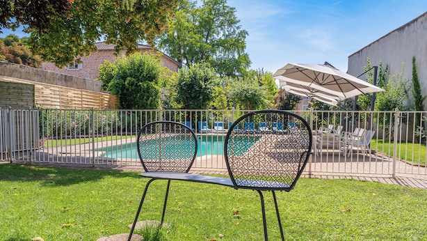 A backyard with a swimming pool, two metal chairs, a table, and a large umbrella. - ibis Styles Macon Centre (Macon)