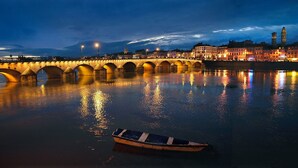 A nighttime view of a river with a bridge and a boat. - ibis Styles Macon Centre (Macon)