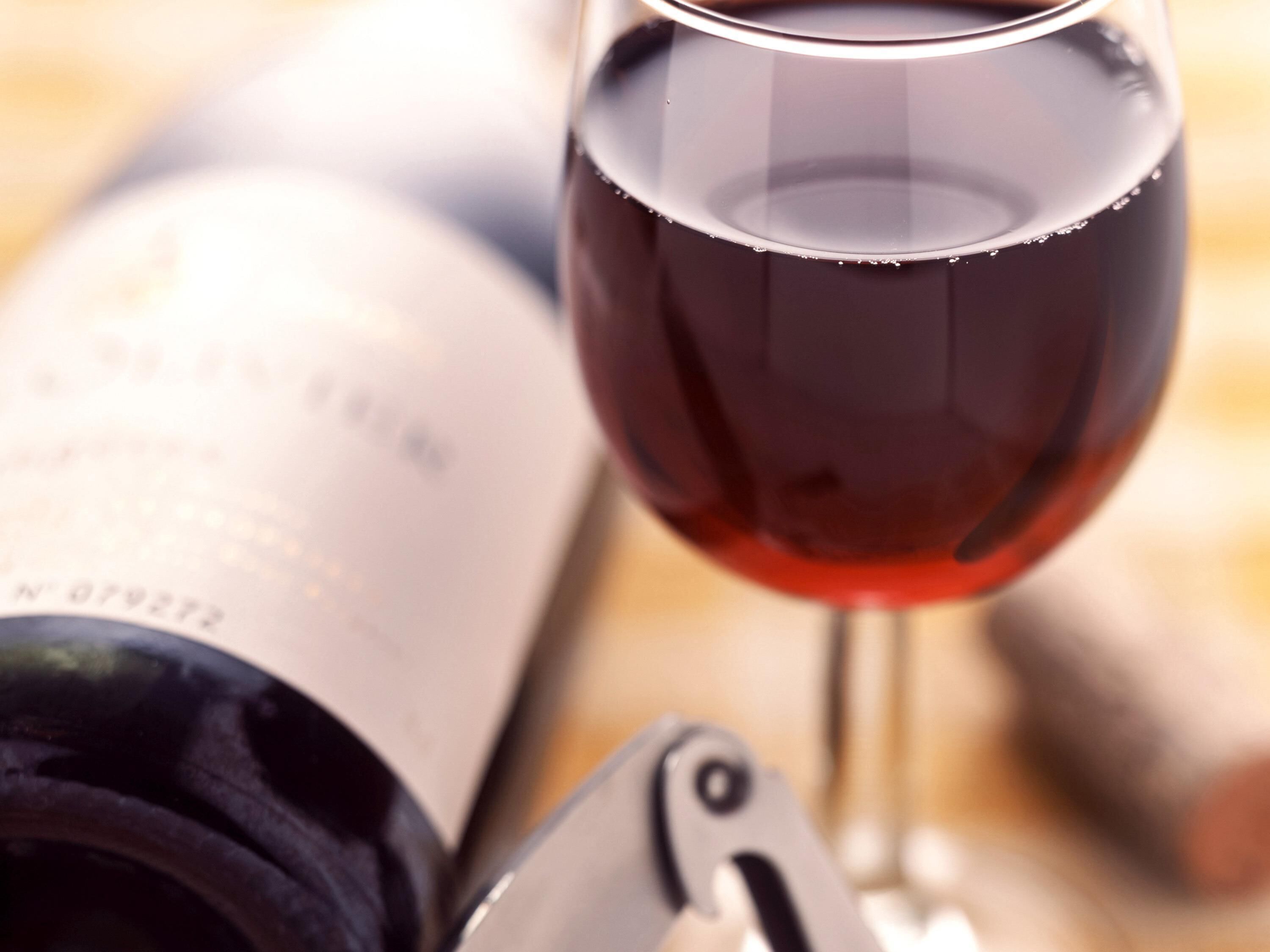A wine bottle and glass on a wooden surface.