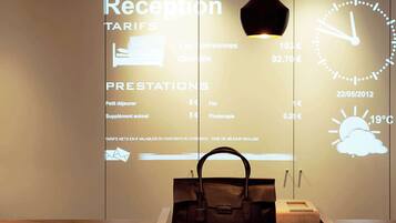 Reception area with digital display showing hotel services and prices.