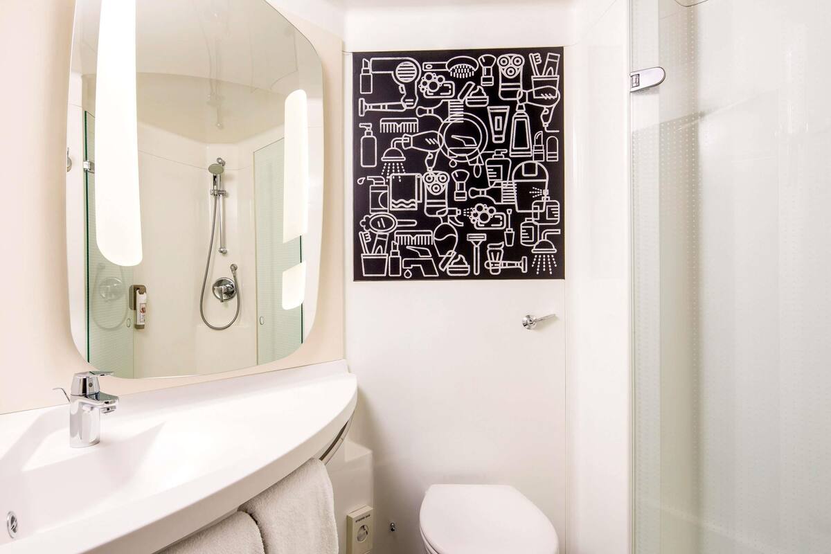 A bathroom with a white sink, mirror, and toilet.
