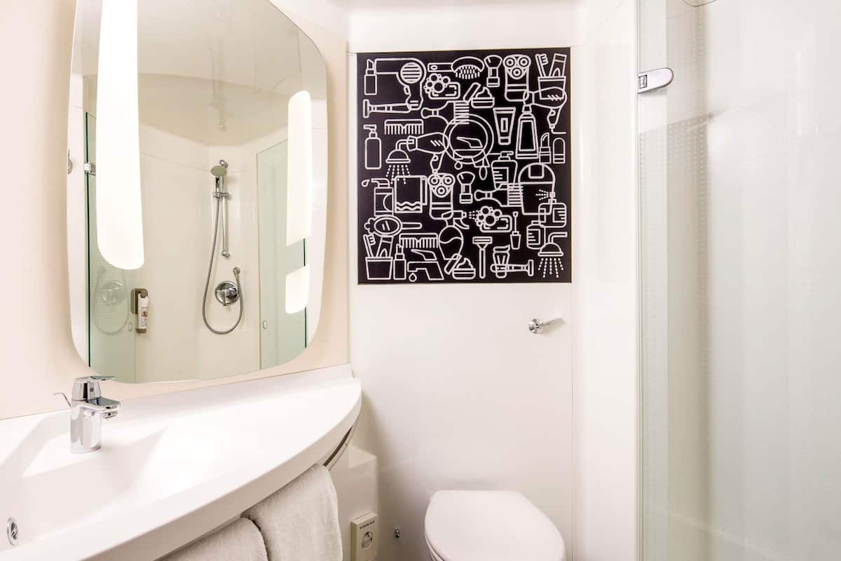 A bathroom with a white sink, mirror, and toilet.