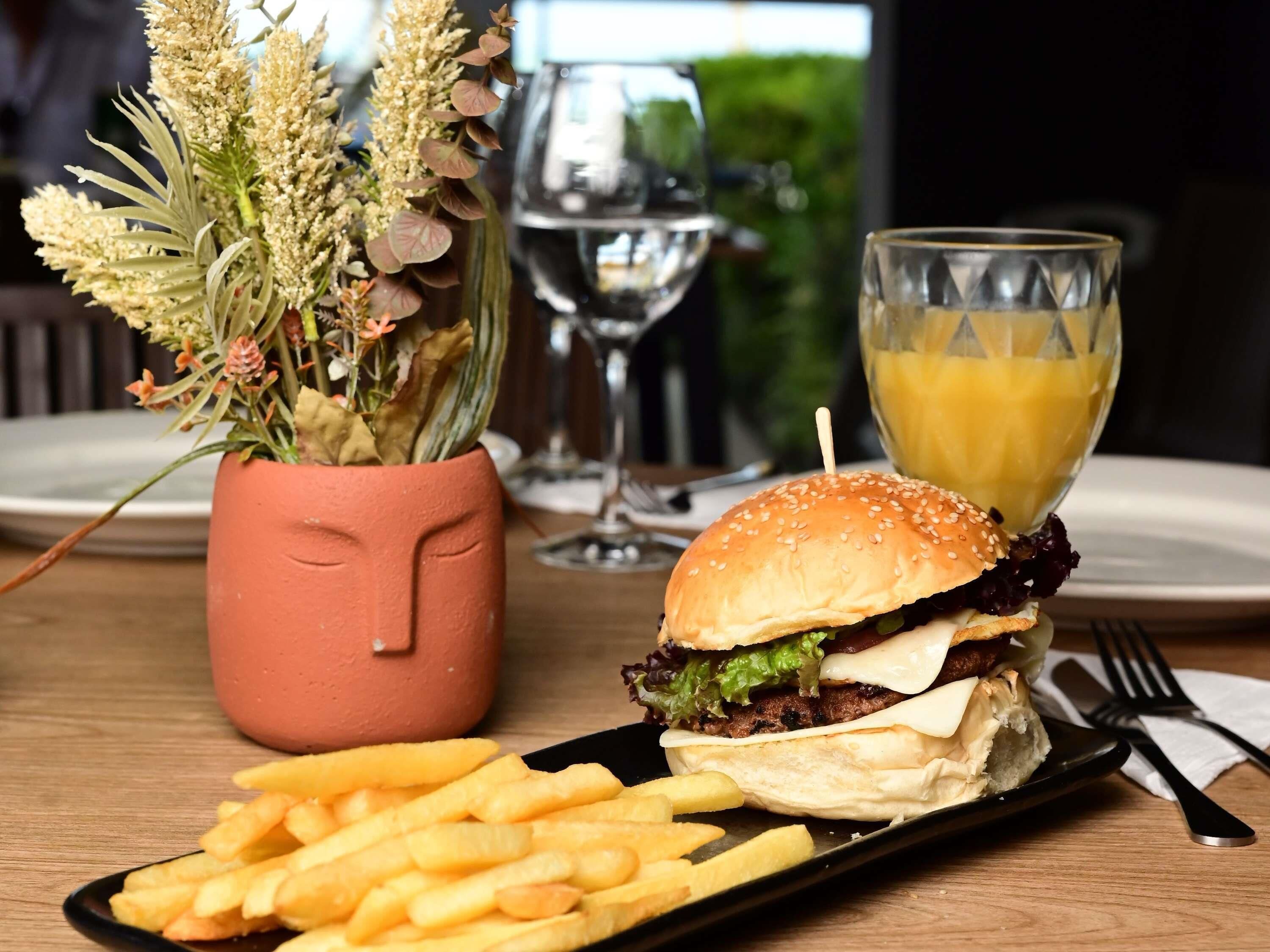A meal with a burger, fries, and a glass of orange juice on a table.