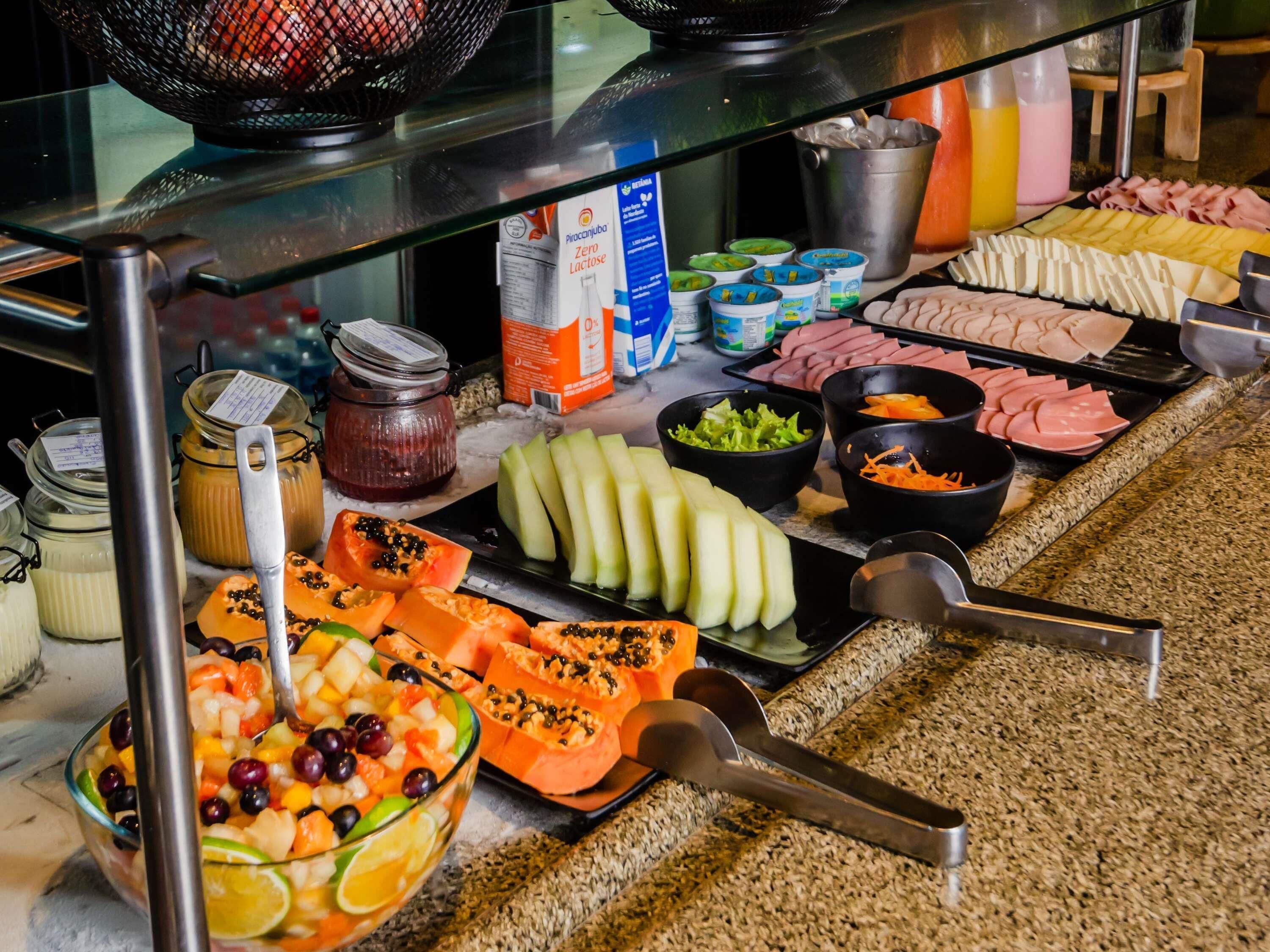Une table de buffet proposant une variété d’aliments, notamment des fruits, des légumes et des viandes.