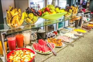 A buffet with various fruits, vegetables, and beverages.