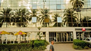 A modern building with a glass facade reflecting palm trees and a clear sky. - Ibis Joao Pessoa (João Pessoa)
