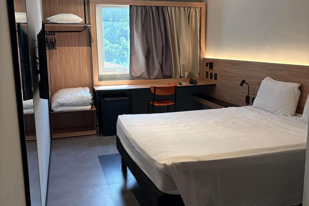 A compact hotel room with a single bed, a desk, and a chair.