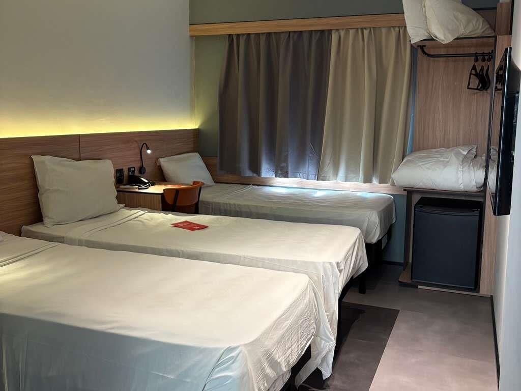 Hotellihuone, jossa on kaksi sänkyä, työpöytä, tuoli, televisio ja pieni kaappi.
