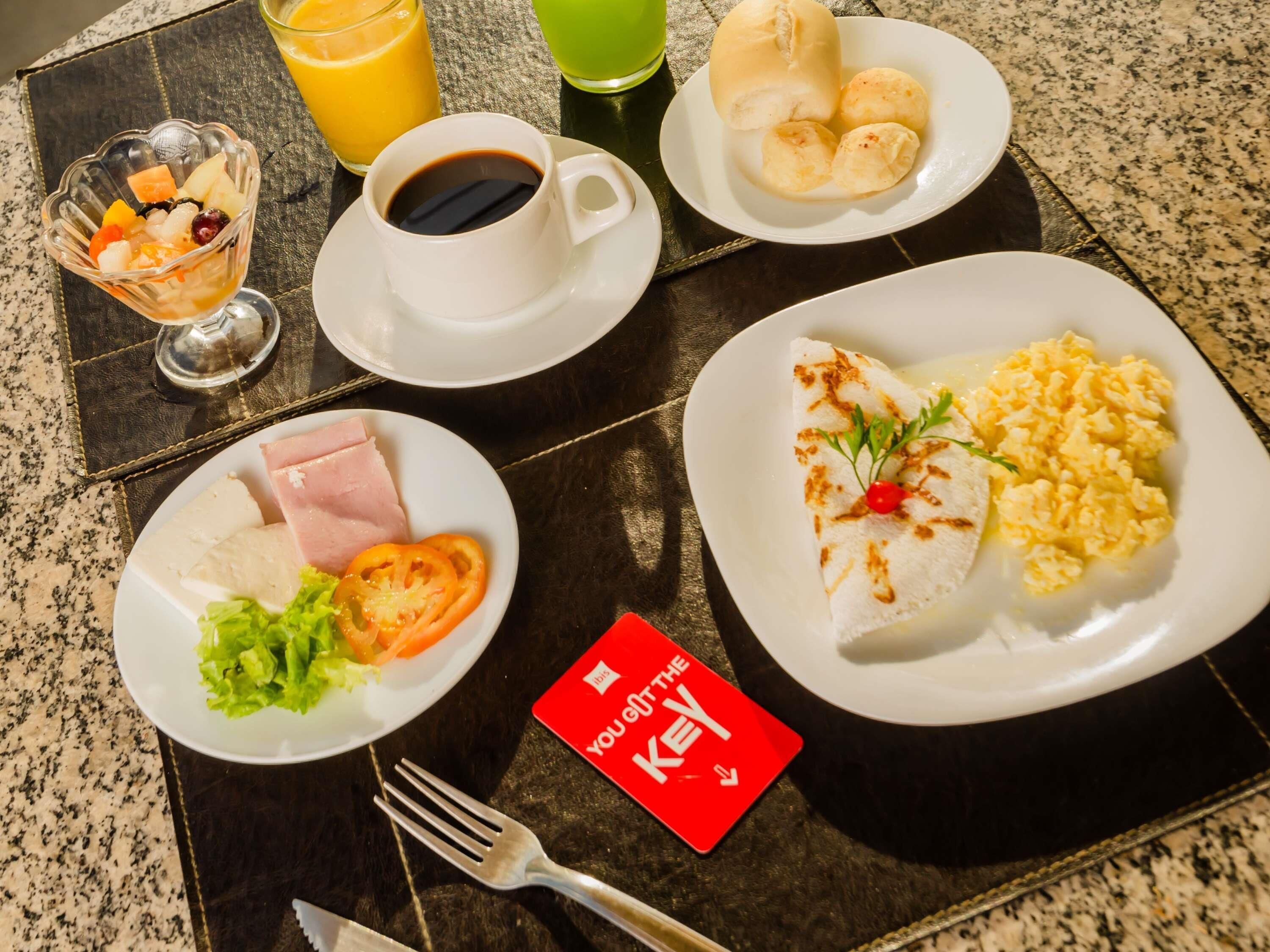 A breakfast setting with plates of food, a cup of coffee, and a glass of orange juice.