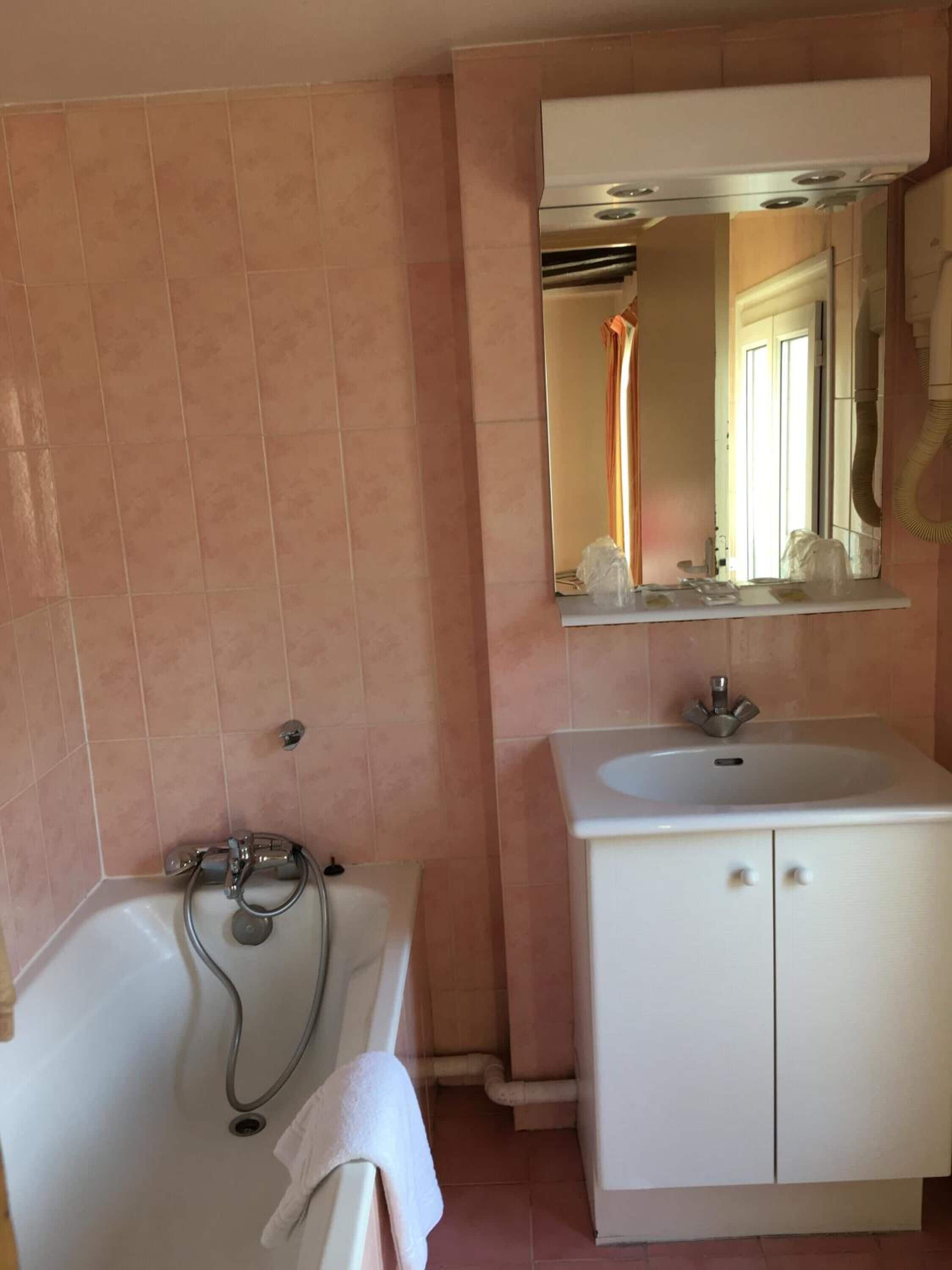 A bathroom with a bathtub, a sink, and a mirror above the sink.