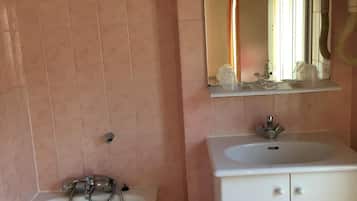 A bathroom with a bathtub, a sink, and a mirror above the sink.