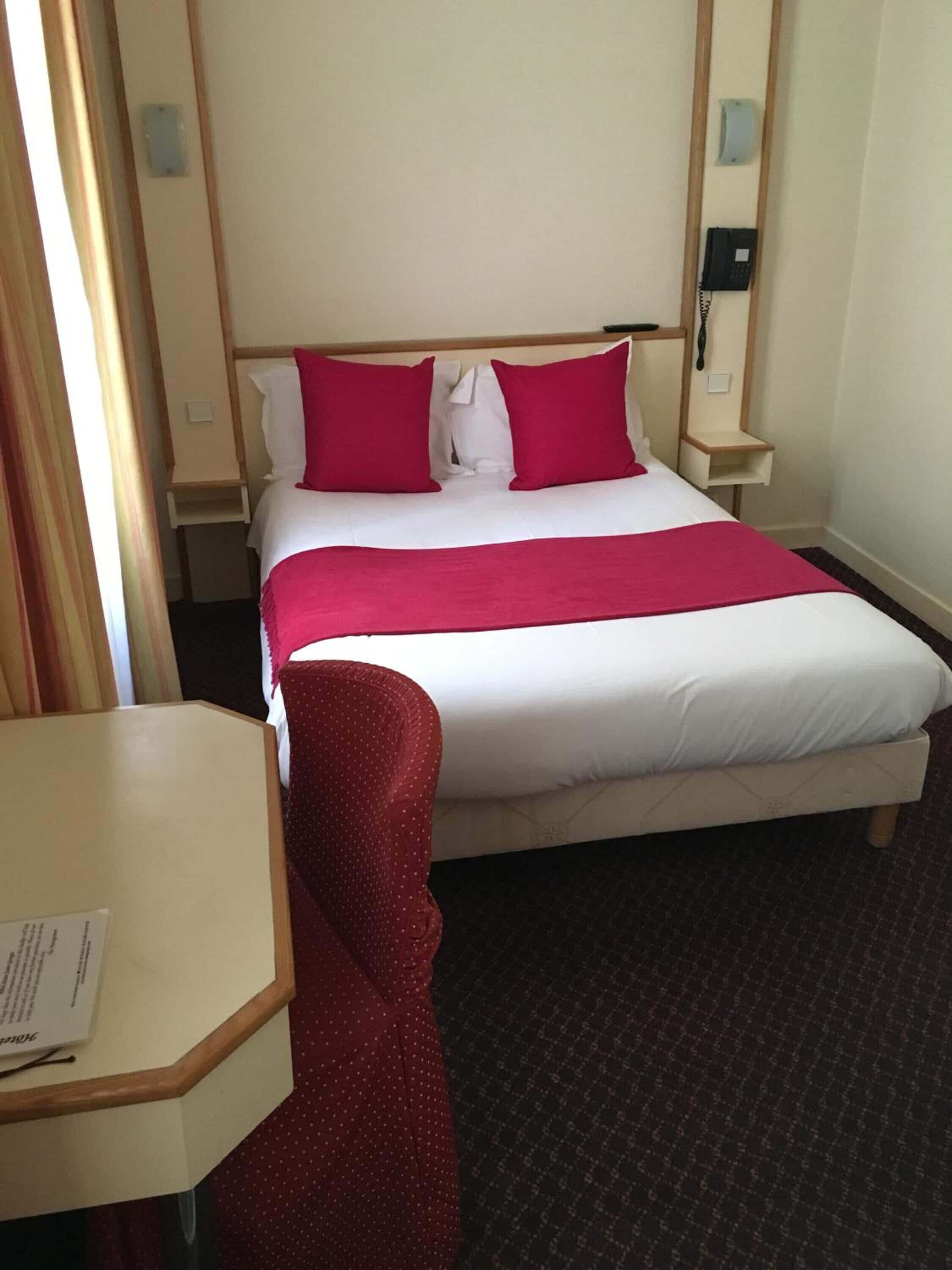 Ett hotellrum med en säng, ett skrivbord och en stol.