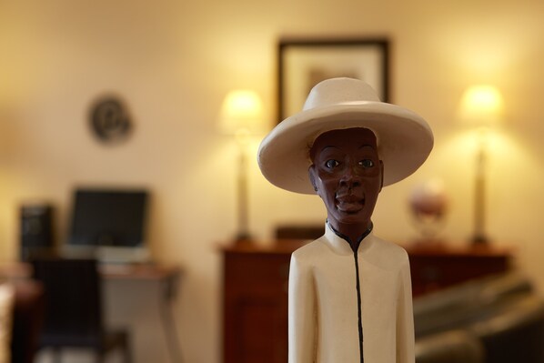 A figurine of a person wearing a hat in a room with a desk, chair, and two lamps.