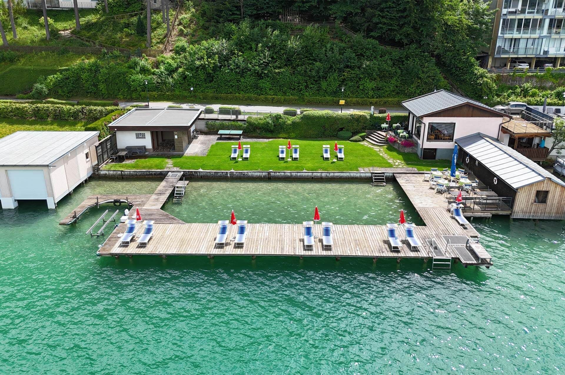 Una proprietà sul lungomare con molo, poltroncine da relax e un piccolo edificio.
