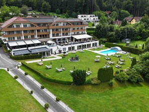 Een hotel met een zwembad, terras en een verzorgd gazon.