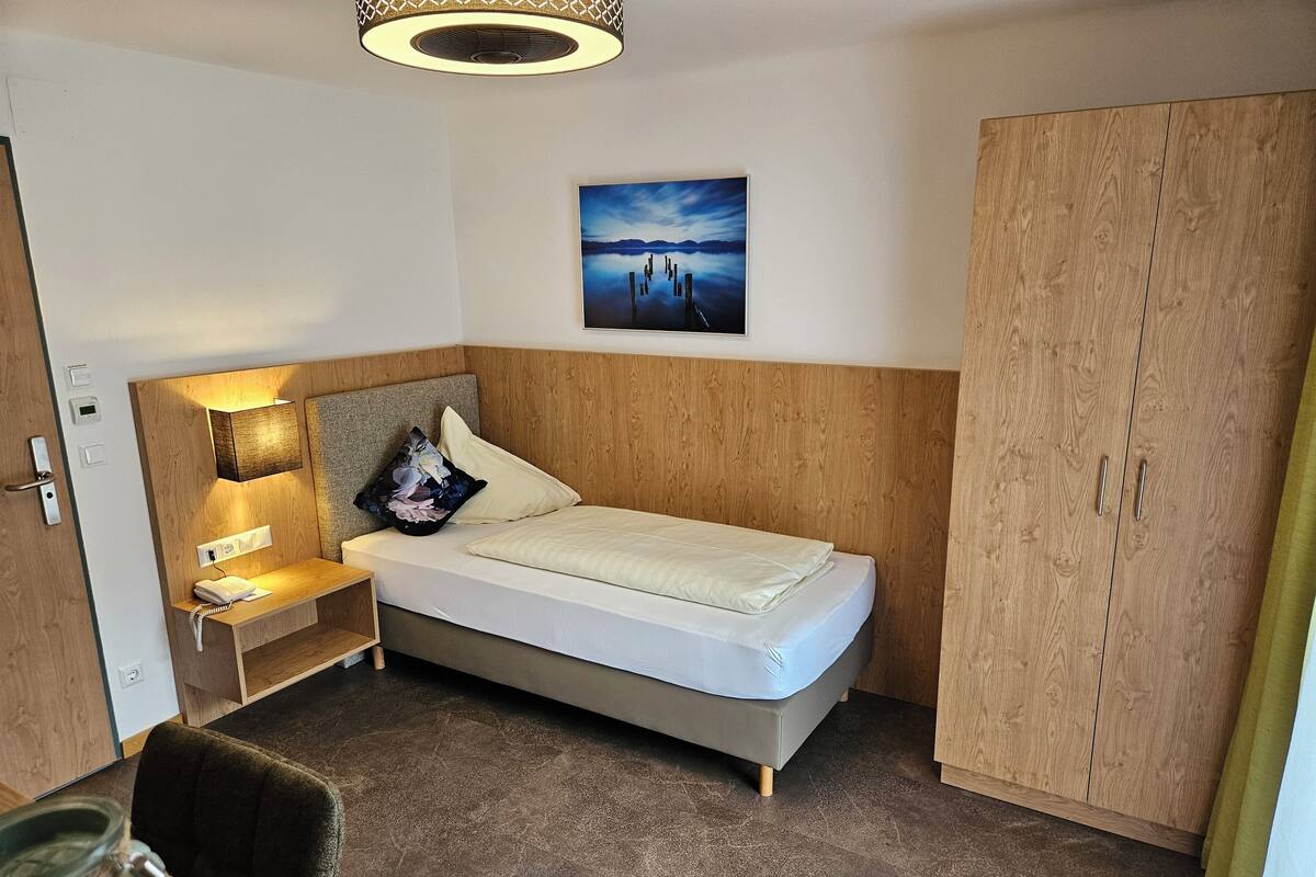Un dormitorio con cama, mesita de noche, lámpara y armario.