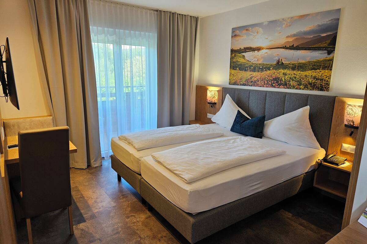 Una habitación de hotel con una cama grande, dos mesitas de noche, un escritorio y una silla.