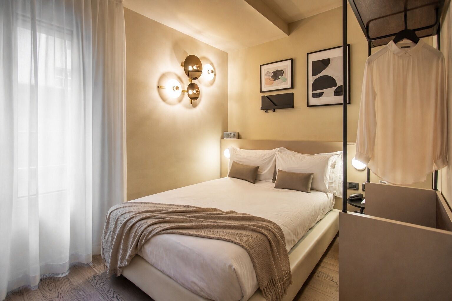 Ein Hotelzimmer mit Bett, Nachttischen, einem Spiegel und Wandleuchten.