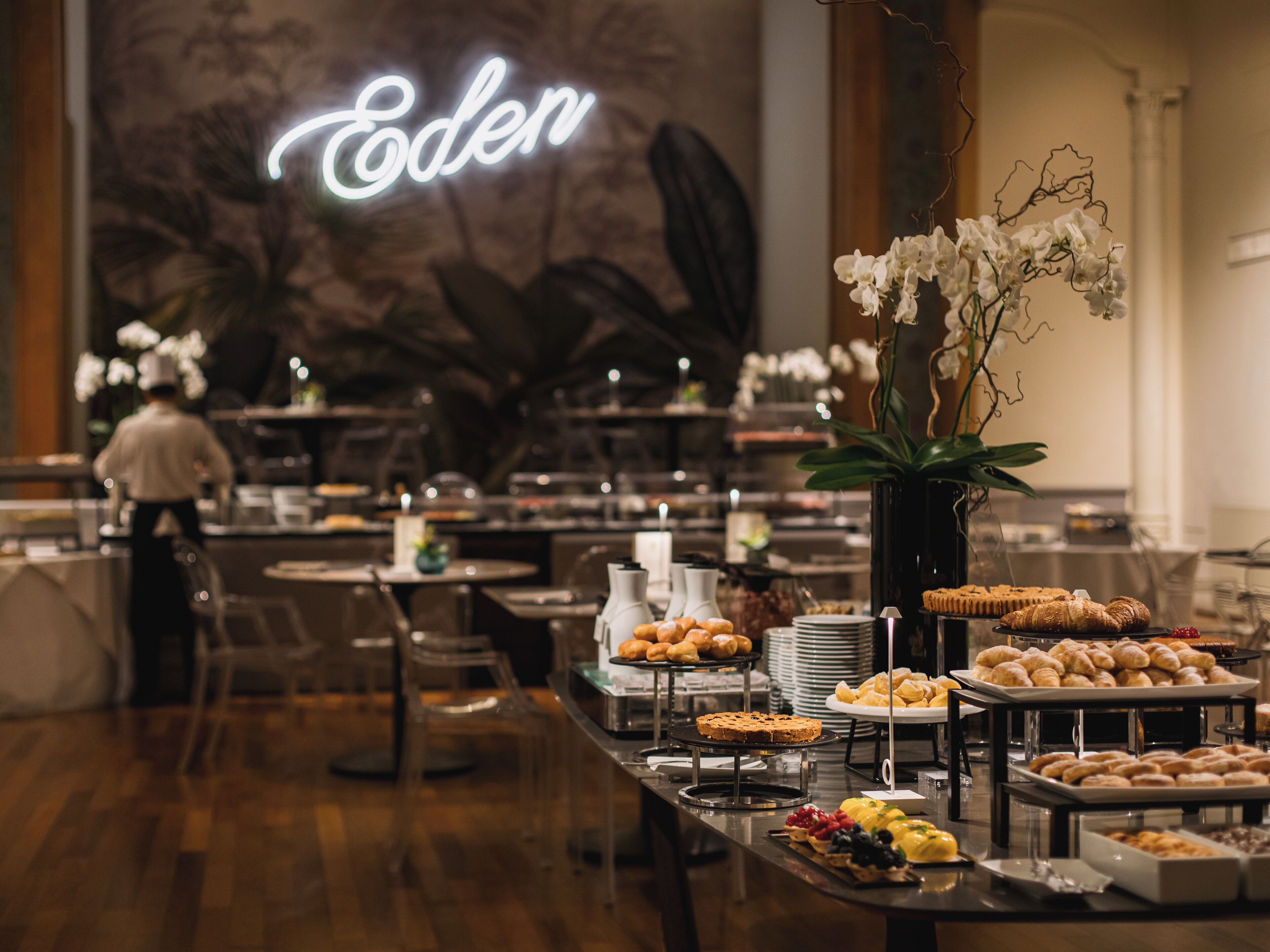 Mesa de buffet con distintos tipos de comida y un letrero de neón al fondo.