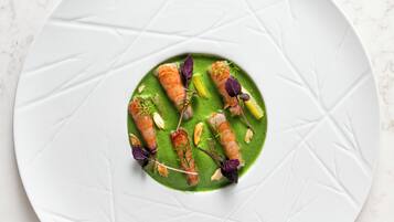Un piatto bianco con salsa verde e cibo su una superficie di marmo.