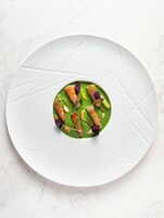 Un piatto bianco con salsa verde e cibo su una superficie di marmo.